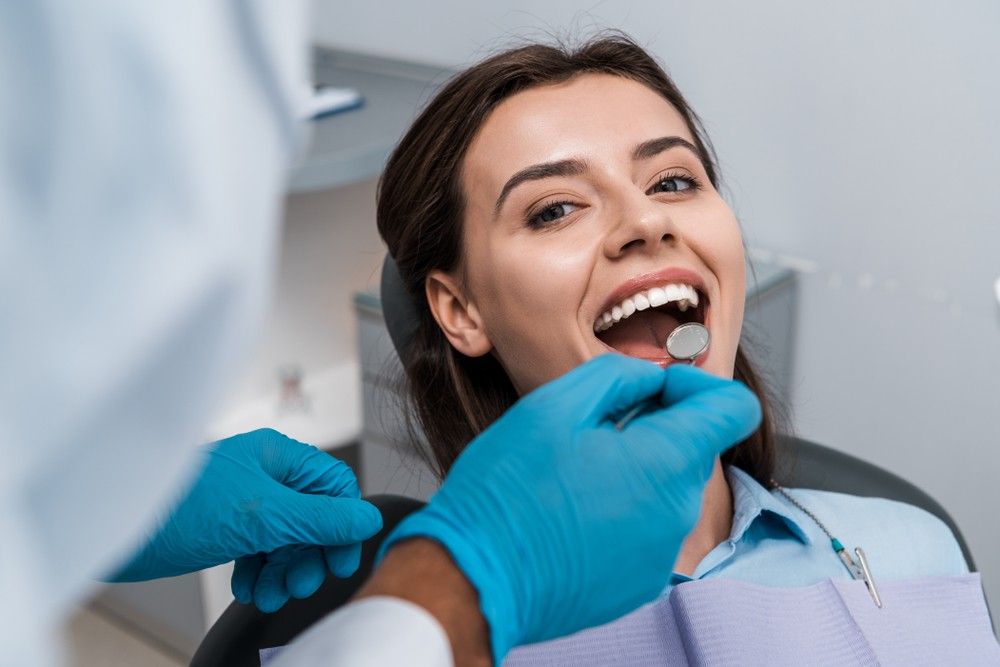 Dentist examining patient teeth using dental mirror during routine dental checkup