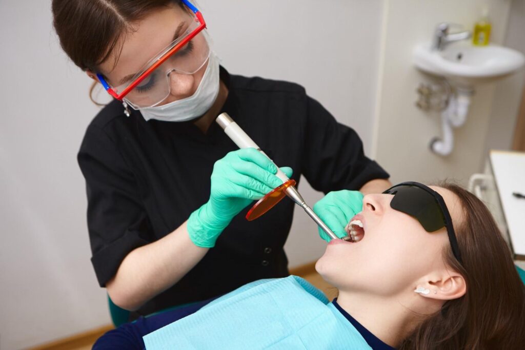 Dental hygienist performing dental cleaning treatment on female patient using dental tools in clinic Monument CO